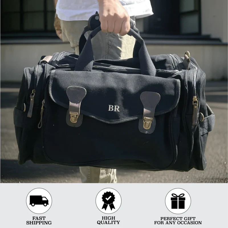Person holding black canvas duffle bag with monogram "BR" and brass buckles, displaying personalized groomsmen travel gift
