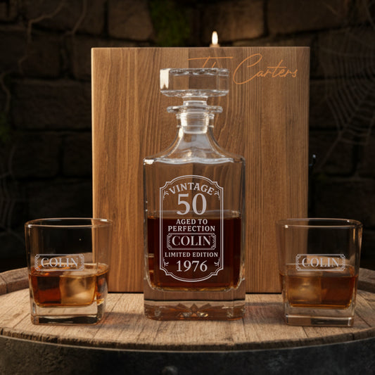 Personalized whiskey decanter and glasses with engraved text on a wooden surface.