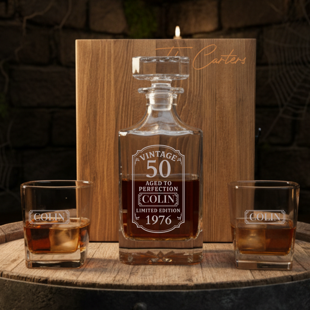 Personalized whiskey decanter and glasses with engraved text on a wooden surface.