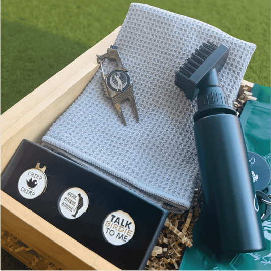 Golf care products including a brush, towel, and accessories on a green grass background