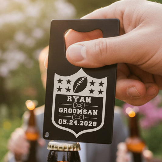 Hand holding a personalized bottle opener with 'Ryan Groomsman' text against a blurred outdoor background.