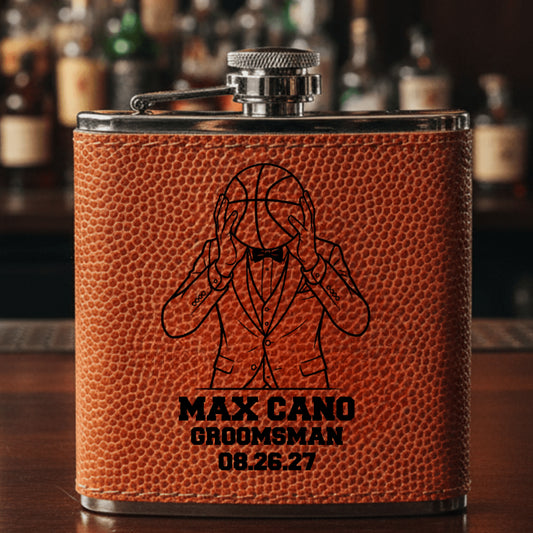 Brown leather basketball groomsmen flask with engraved design and text on a bar counter