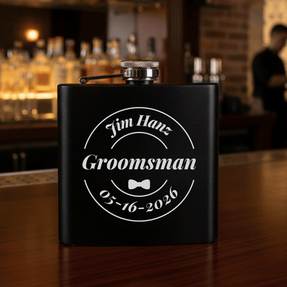 Black flask with 'Jim Hanz Groomsman 05-16-2026' text on a bar counter.