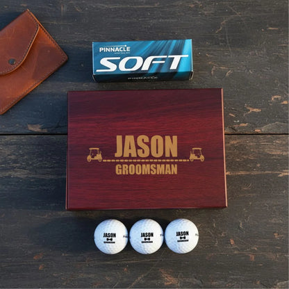 Personalized golf ball set with 'JASON GROOMSMAN' on a wooden box, golf balls, and a Pinnacle Soft box on a rustic wooden surface.