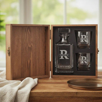Glass decanter set with two glasses in a wooden box on a wooden surface.