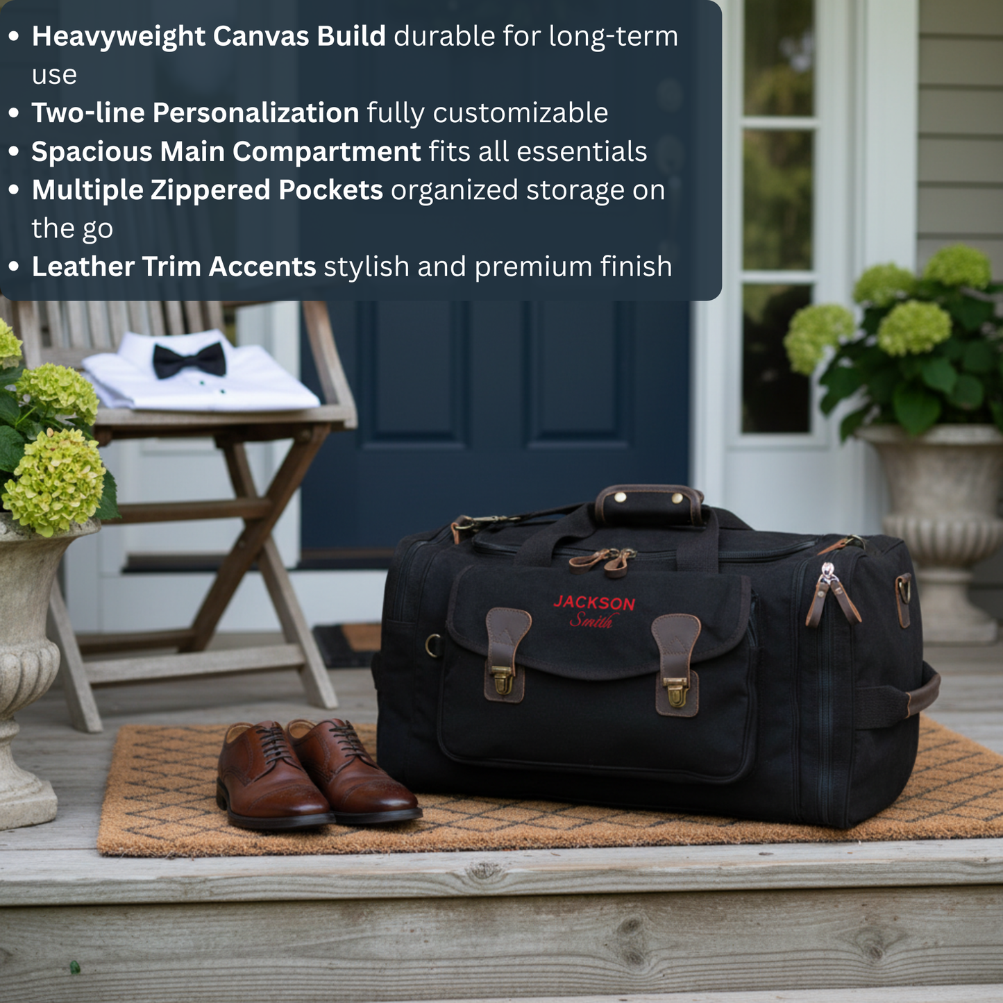 Black canvas duffle bag with brown leather trim and brass hardware, personalized with sample text "JACKSON Smith" in red embroidery, displayed on porch with brown shoes