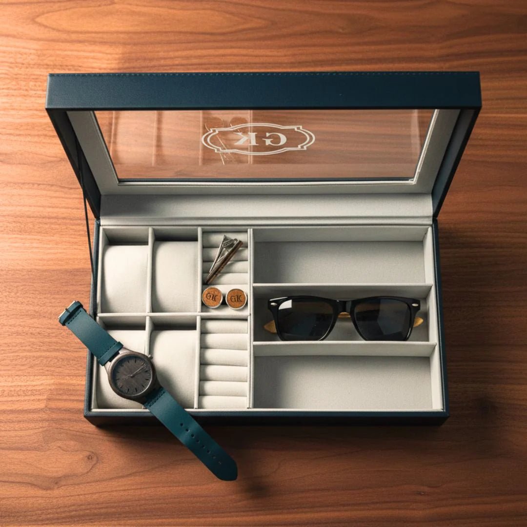 Open jewelry box with watch, sunglasses, and other items on a wooden surface