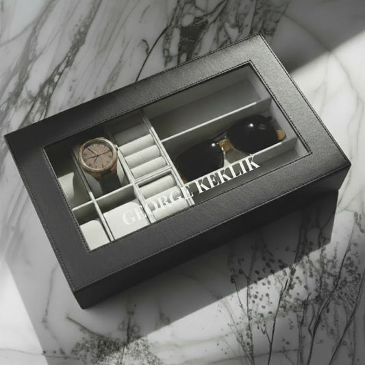 Gray jewelry box with watch, earrings, and other items on a marble surface