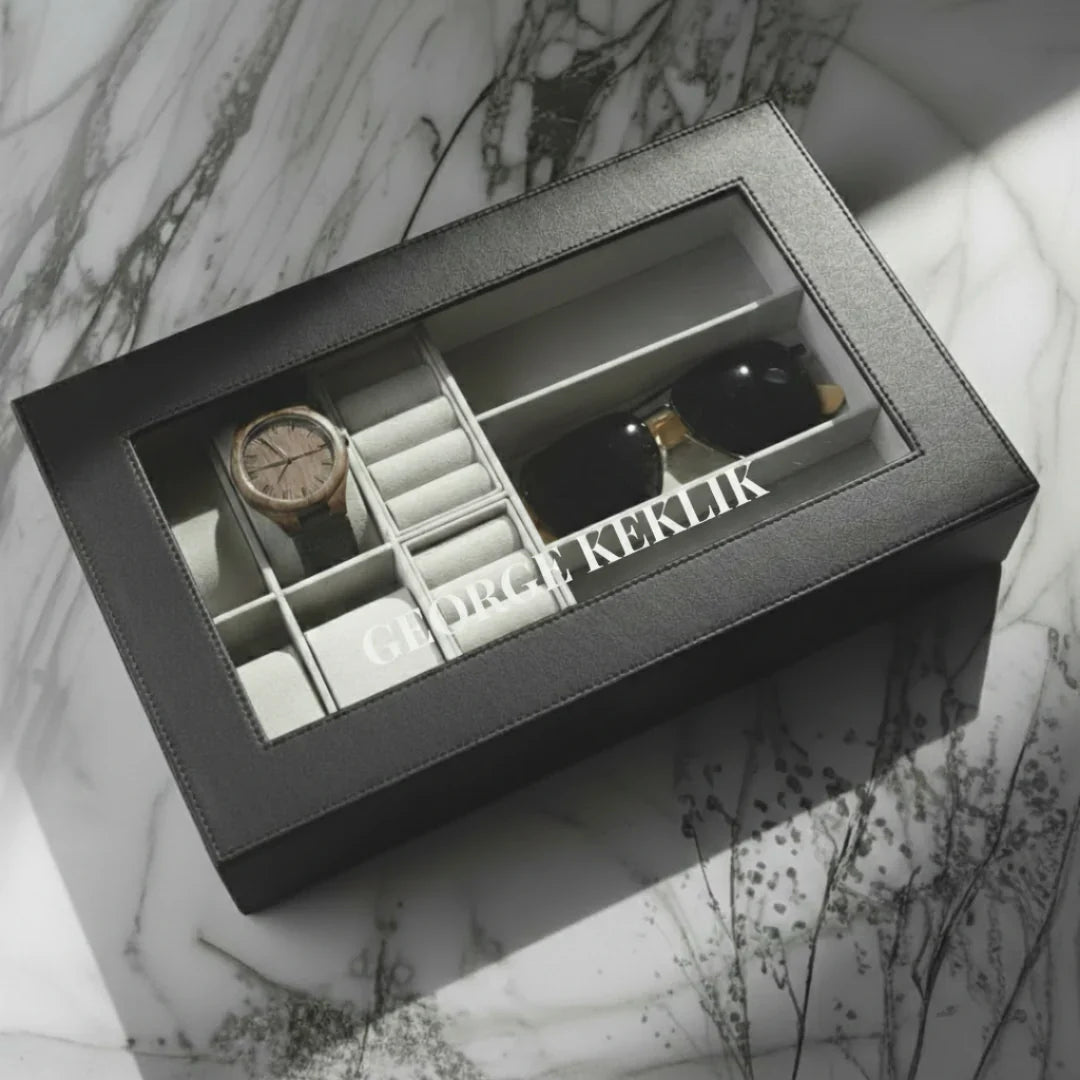 Gray jewelry box with watch, earrings, and other items on a marble surface
