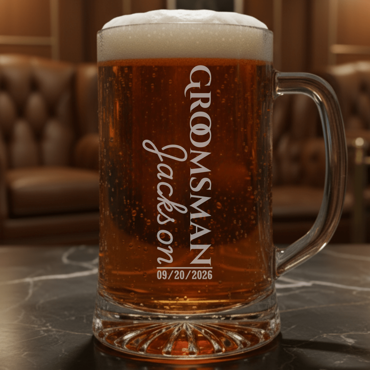 Personalized glass mug with beer and 'Groomsman Jackson' engraving on a marble surface.