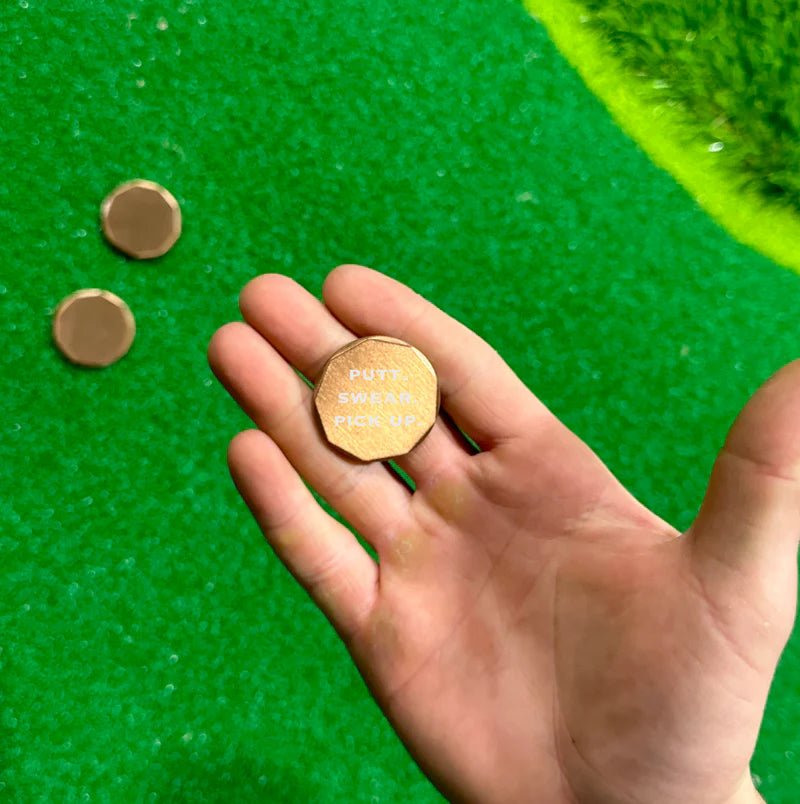 Copper golf ball marker with humorous design, lightweight and perfect for pocket carry