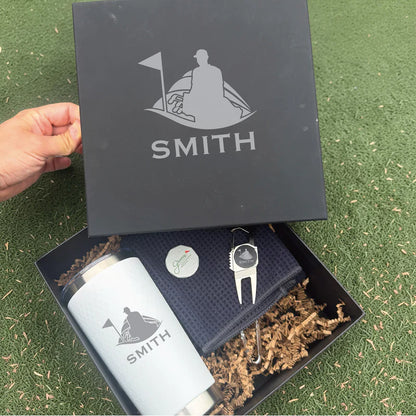 Personalized golf-themed gift box with engraved flask, divot tool, and ball marker showing sample name "SMITH" with golfer and flag design.