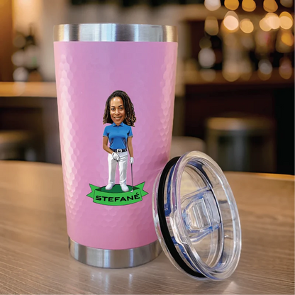 Pink stainless steel tumbler with custom caricature of golfer holding club and example name "Stefane" on green banner, shown with clear lid removed.