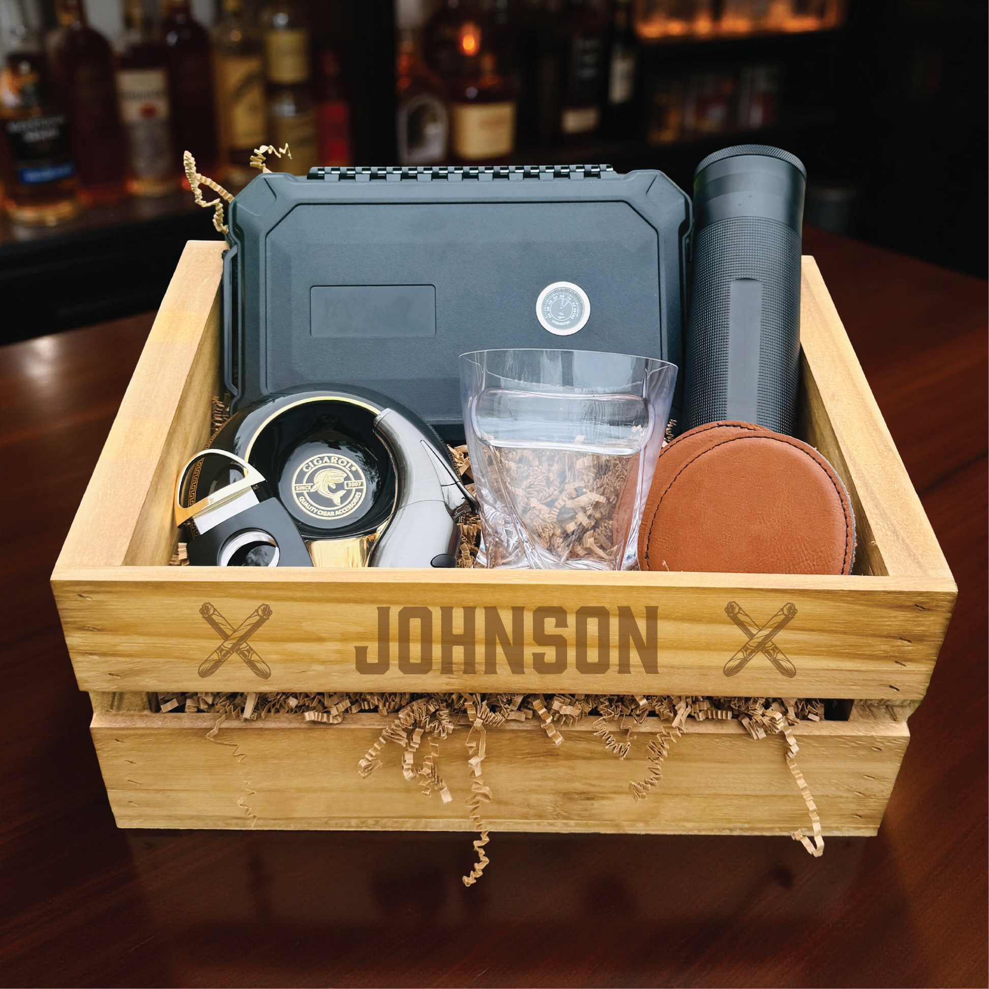 Personalized groomsmen cigar gift set in an engraved wooden crate with a cigar humidor and whiskey glass.