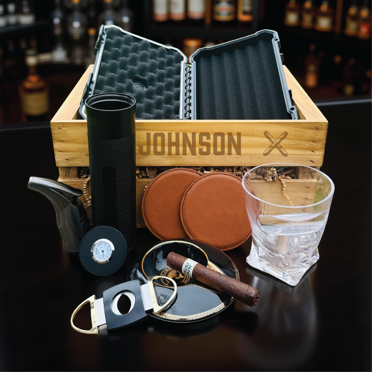 Personalized groomsmen cigar gift set in an engraved wooden crate with a cigar humidor and whiskey glass.