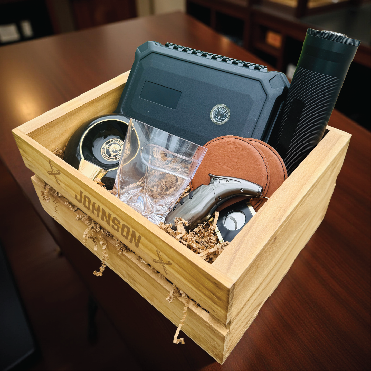 Personalized groomsmen cigar gift set in an engraved wooden crate with a cigar humidor and whiskey glass.