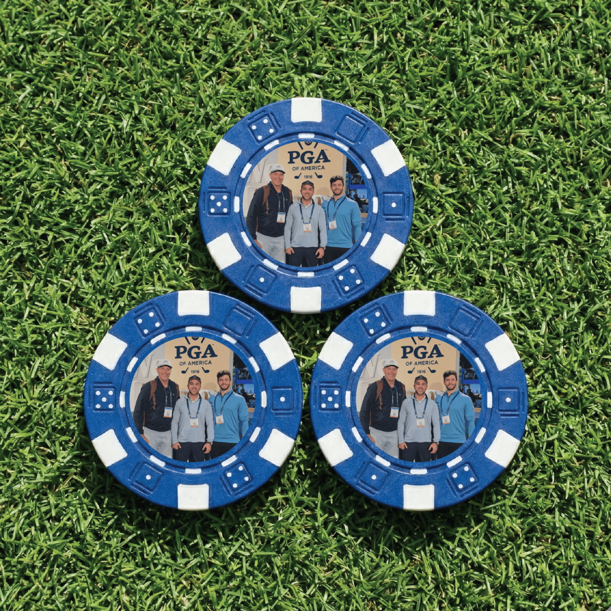 Three blue poker chips with PGA of America branding on a grass background