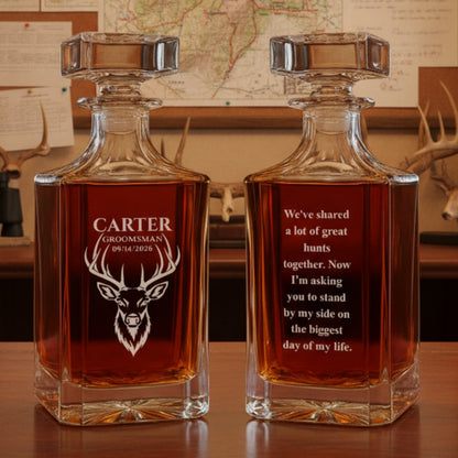 Pair of crystal decanters with sample personalization: deer head design with "CARTER GROOMSMAN 09/14/2026" on one side, and wedding proposal message on the reverse, filled with amber liquid.