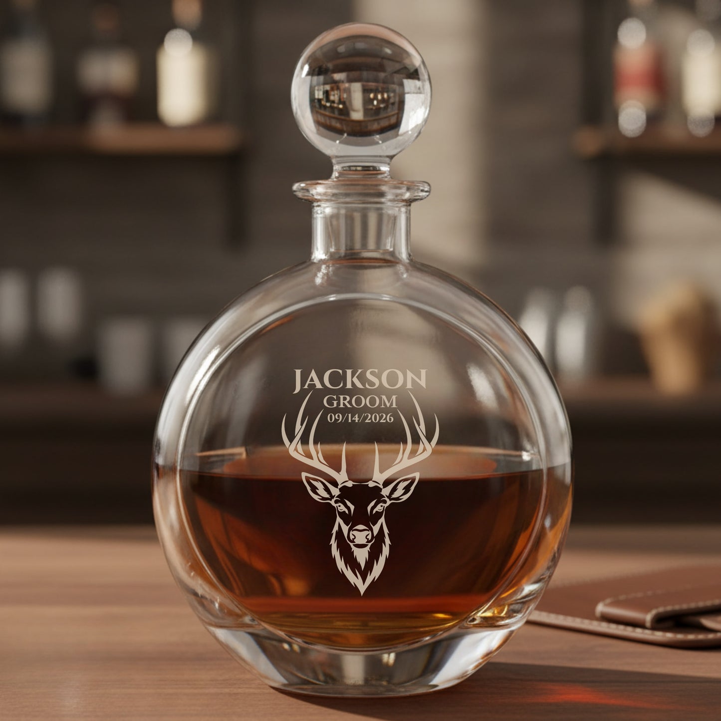Engraved decanter with spherical stopper filled with amber liquor, featuring sample personalization reading "JACKSON GROOM 09/14/2026" above a stag head design