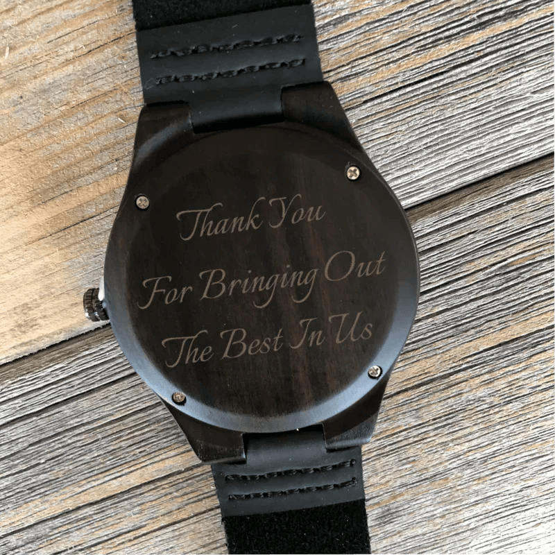 Black wood watch with leather strap, engraved sample text reading "Thank You For Bringing Out The Best In Tls" on the face.