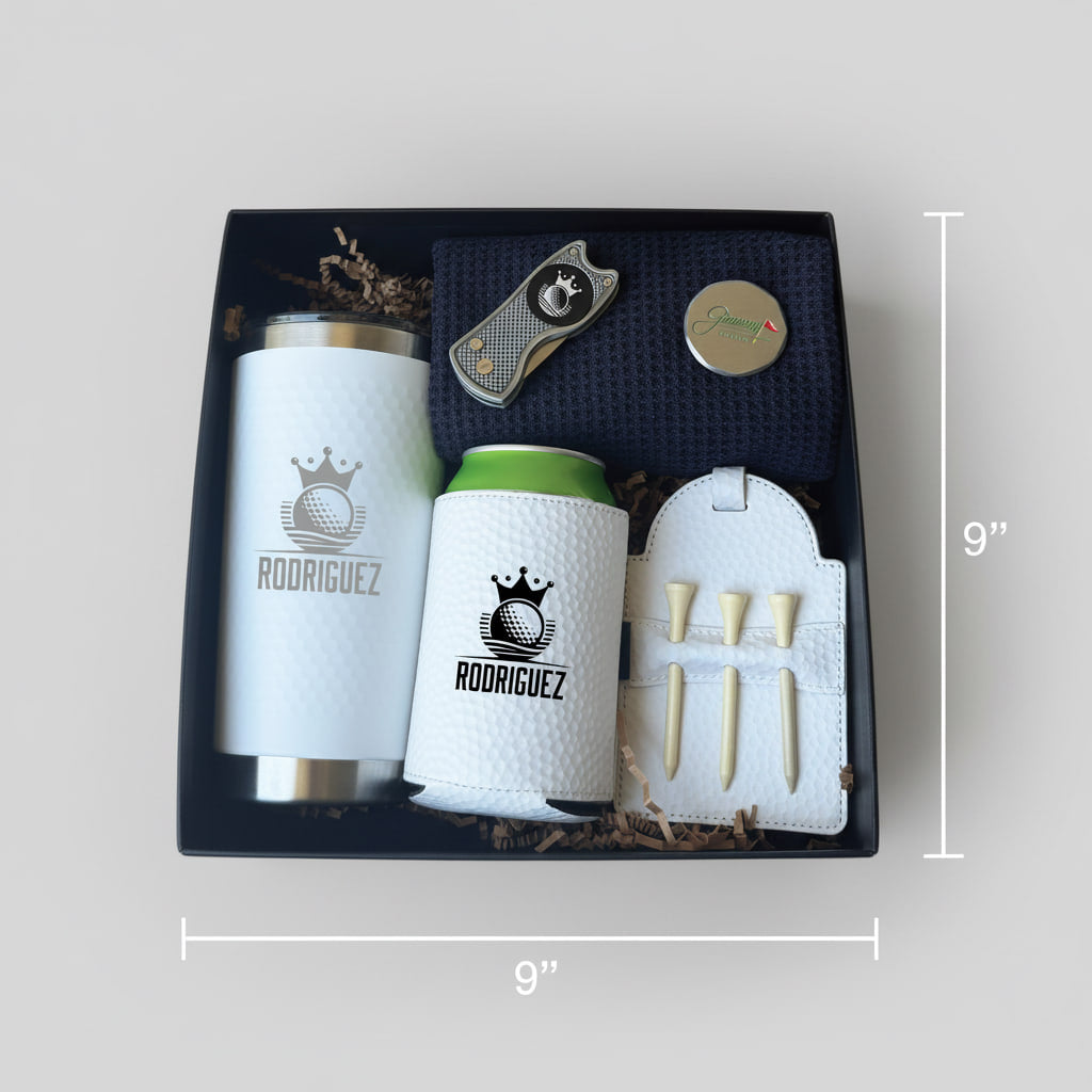 Black gift box containing engraved insulated tumbler, golf-themed can cooler, white golf towel with tees, cigar cutter, and round personalization sample labeled "Rodriguez