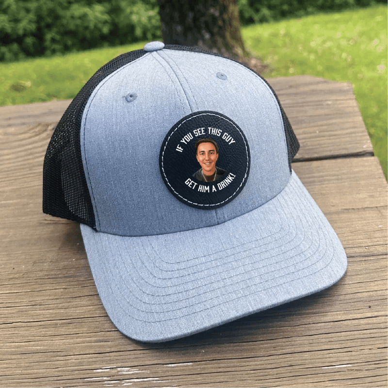 Light gray and black trucker cap with circular patch featuring photo sample and text "If you see this guy, get him a drink