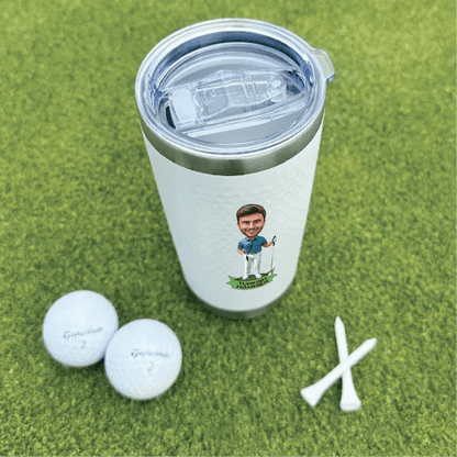 White insulated tumbler with sample golf-themed caricature personalization, displayed with golf balls and tees on green turf.