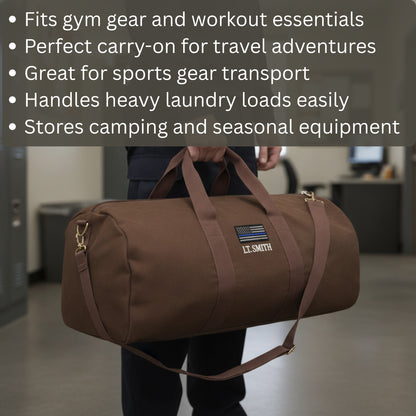 Brown canvas duffle bag with sample personalization reading "LT. SMITH" and thin blue line flag patch, carried by person in indoor setting.