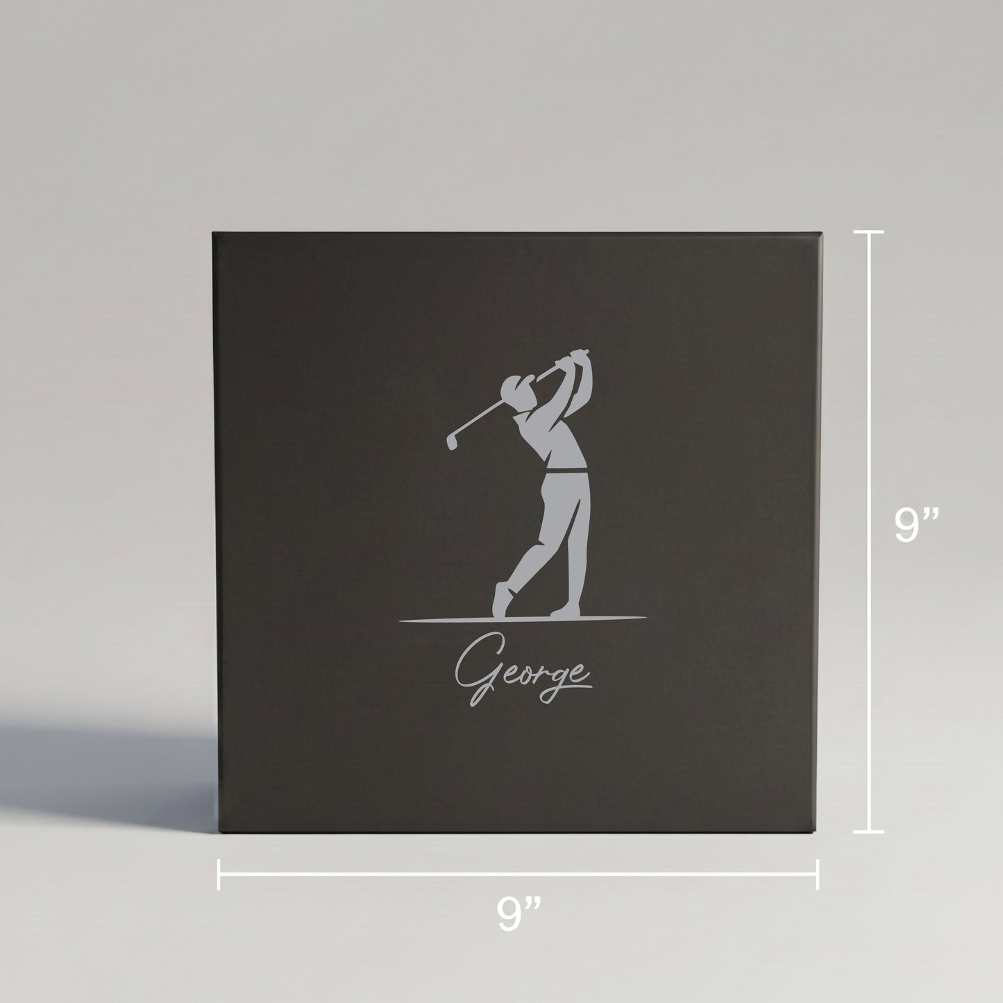 Dark gray gift box with engraved golfer silhouette and sample name "George" below, measuring 9 inches square