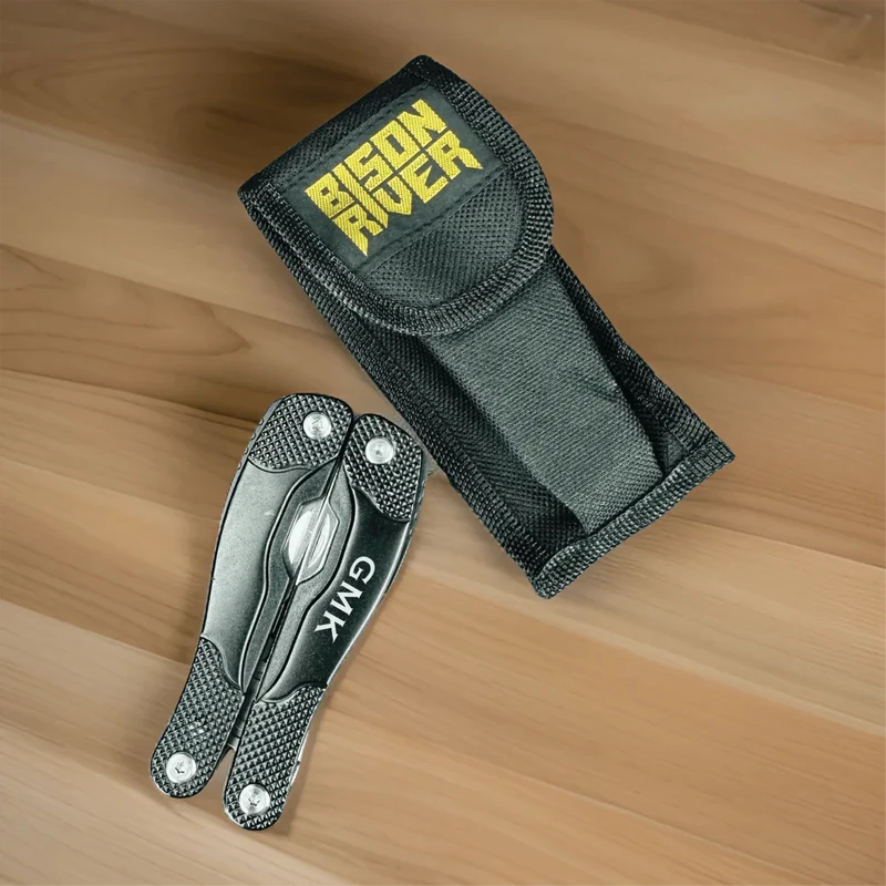 Multi-tool with textured handle and engraved blade next to black nylon carrying sheath with yellow logo patch on wooden surface.