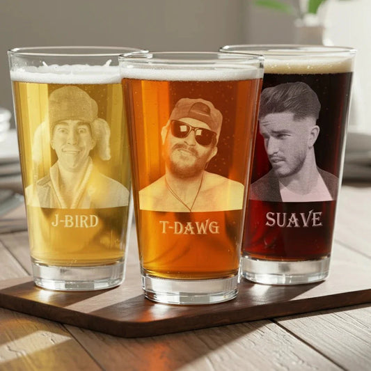 Three beer glasses with engraved faces and names on a wooden tray.