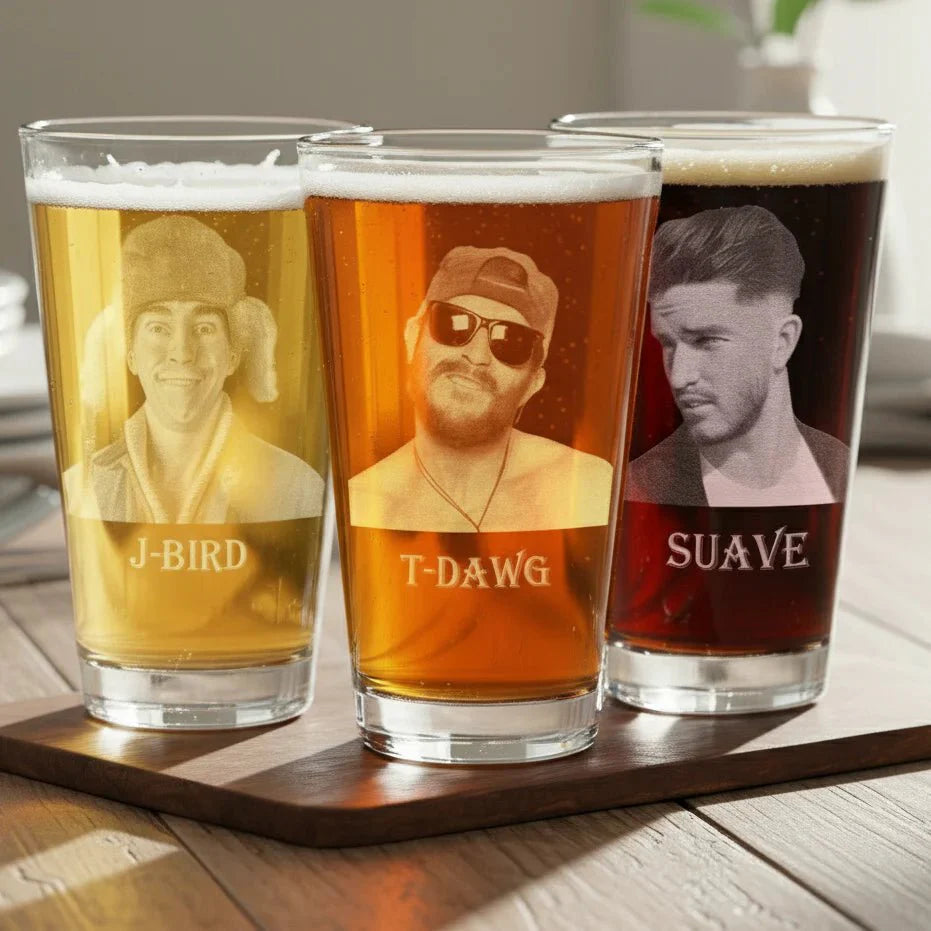 Three beer glasses with engraved faces and names on a wooden tray.