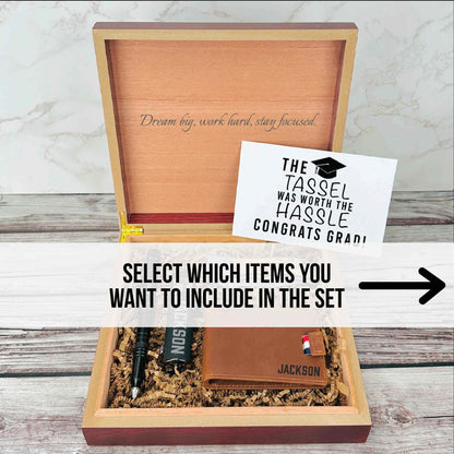 Wooden box with engraved "Dream big, work hard, stay focused" on lid, containing sample personalized leather wallet with name "Jackson" and other gift items.