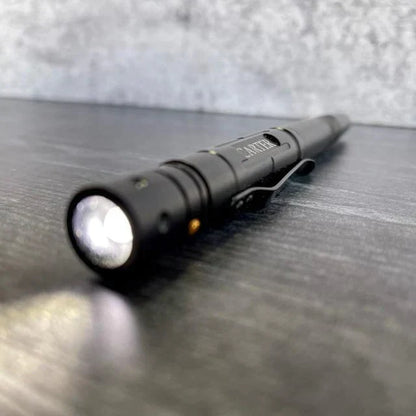 Black tactical flashlight with illuminated beam on dark surface, showing engraved logo detail on barrel