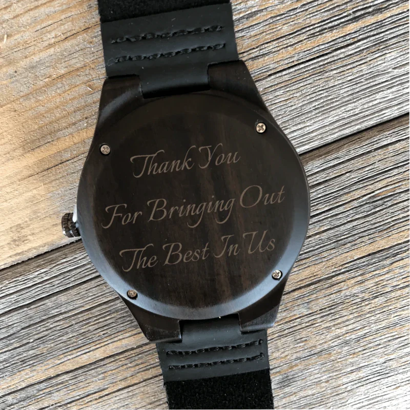 Black wood watch with leather strap, engraved sample text reading "Thank You For Bringing Out The Best In Tls" on the face.